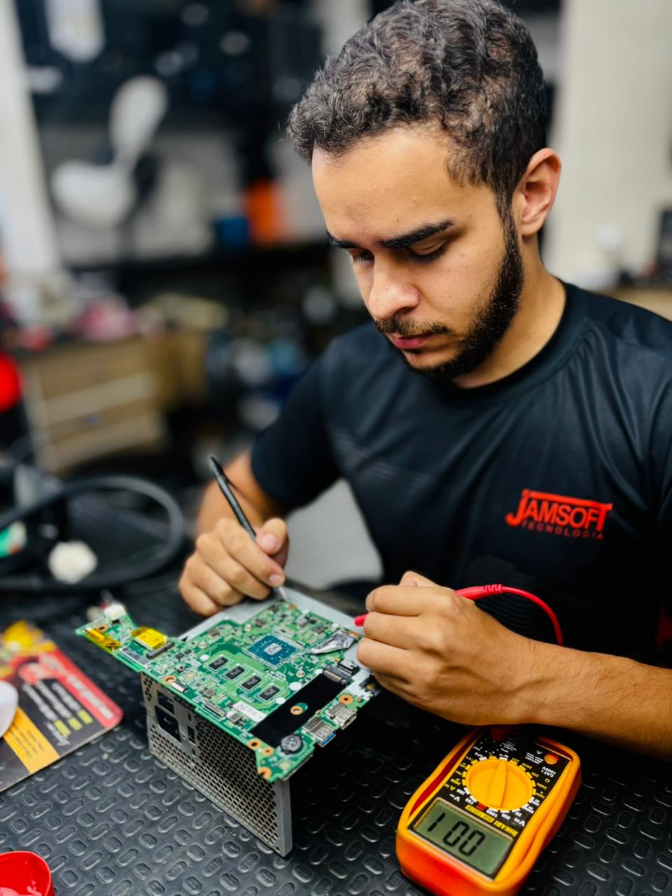 Técnico Gustavo especializado consertando placa-mãe de notebook, realizando manutenção eletrônica em laptop